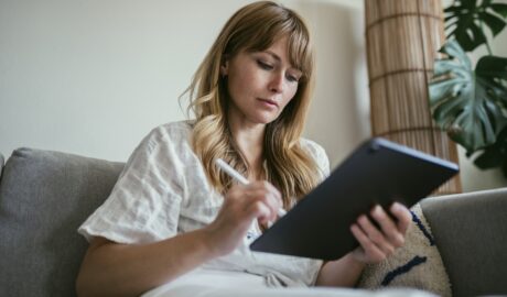 Woman using a stylus writing on a digital tablet