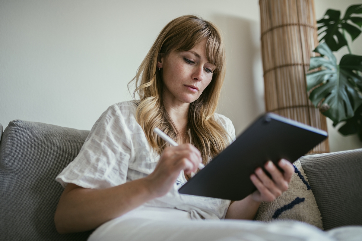 Woman using a stylus writing on a digital tablet