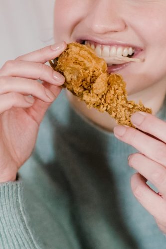 Photo by Tim Samuel: https://www.pexels.com/photo/hungry-woman-biting-fried-delicious-chicken-6697382/